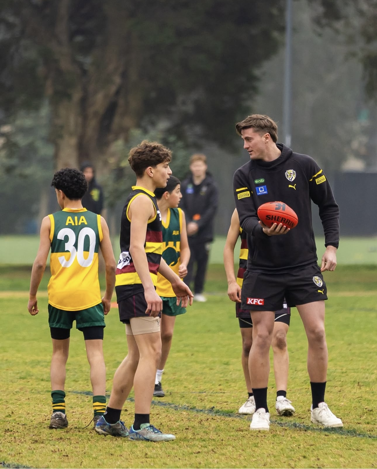 Jacob Blight coaching junior footballers on the field