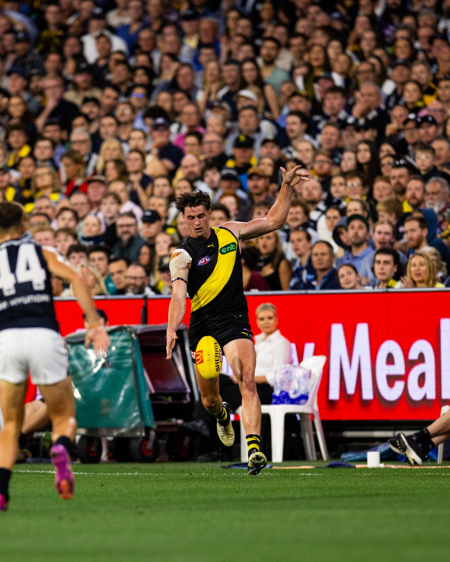 Jacob Blight kicking for Richmond in front of a packed AFL crowd